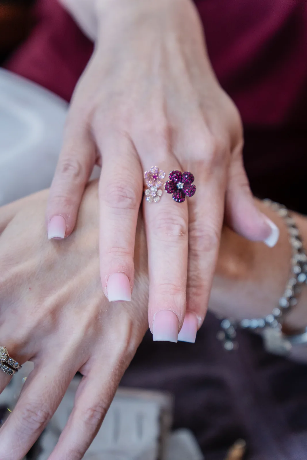 Pink-to-white ombré nails beside a purple flower ring